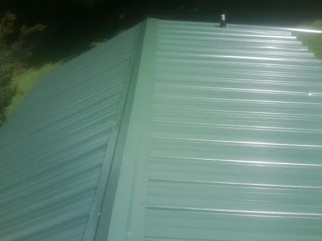 New green metal panels meeting at the ridge of a roof — Flat Roof Repair work by our crew in Saint Helena