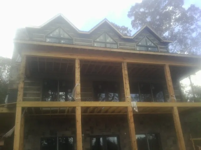Dormers and porch framing on a large log home under construction — Roof Coating work by our crew in Saint Helena