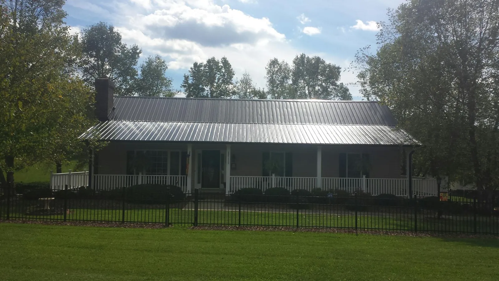 Gray metal roof on a brick ranch with a full width front porch — Gutter Guard Installation work by our crew in Saint Helena
