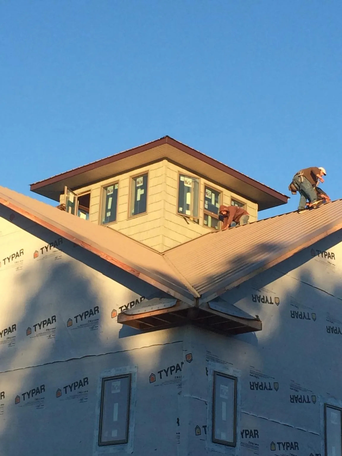 Roofers working around a rooftop cupola on a new metal roof at sunset — Roof Waterproofing in Saint Helena by Roofing Brothers
